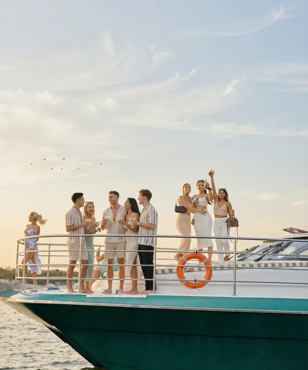 Guests toasting on a yacht's bow at sunset, photographed by Beau